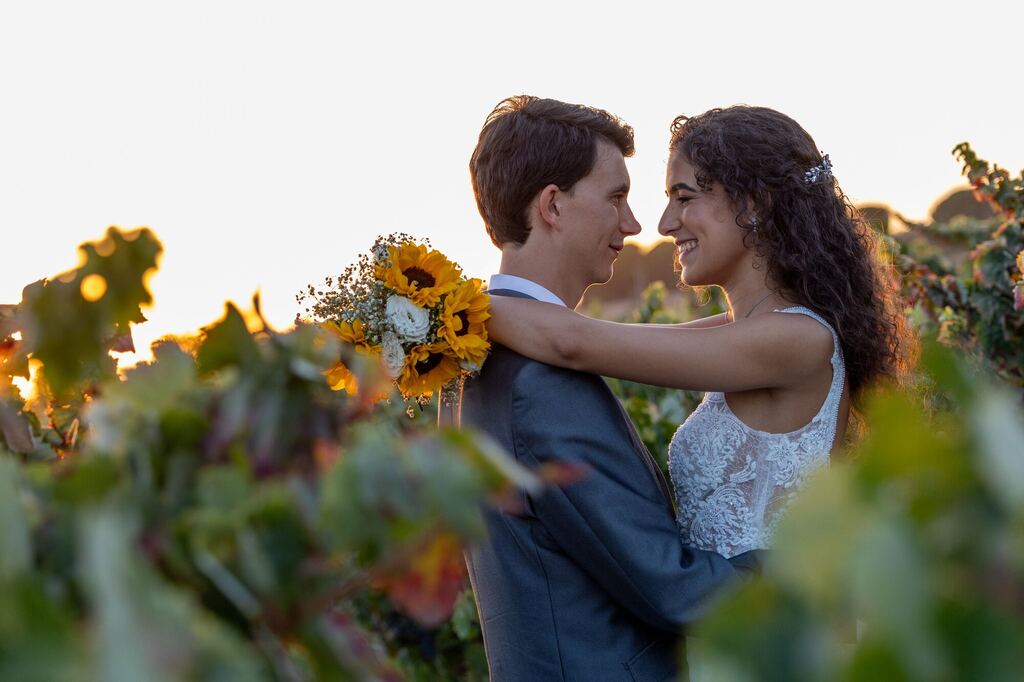 Noivos na vinha com bouquet de girassóis